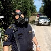 En polisman med en gasmask vid avspärrningarna vid Möljneryd utanför Ronneby, där ett Jas Gripen flygplan kraschade under förmiddagen.