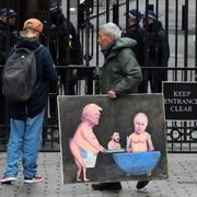Konstnären Kaya Mar håller i en tavla föreställandes Trump, Zelenskyj och Putin i en demonstration i London i april.