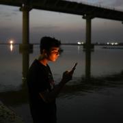 Illustrationsbild, en ung kille kollar mobilen vid floden Ganges i Prayagraj. Rajesh Kumar Singh / AP