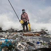 Kinson Jayalath fiskar på en förorenad strand full av skräp.