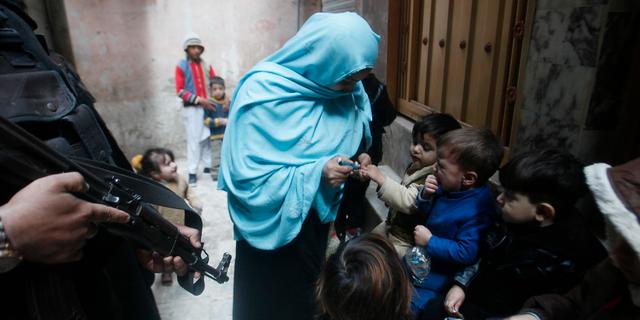 Poliser vaktar hälsoarbetare som vaccinerar mot polio. Muhammad Sajjad / TT NYHETSBYRÅN