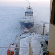 Arkivbild på en isbrytare och SMHI:s karta över aktuella varningar.