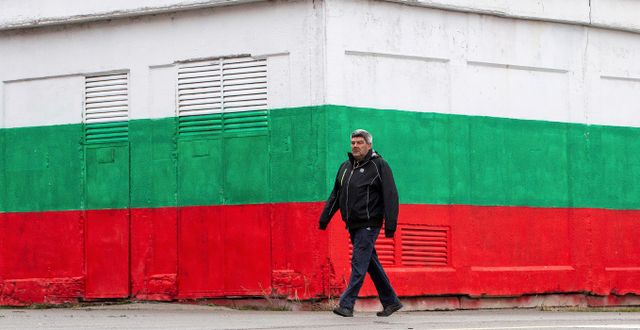 En man framför en vägg målad i Bulgariens färger. Visar Kryeziu / AP