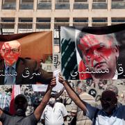 Demonstranter håller upp affischer av Riad Salameh, guvernören för Libanons centralbank, till höger, och Makram Sadir, generalsekreterare för Association of Banks in Lebanon. 