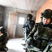 En kvinnlig soldat i full stridsutrustning under övning i markstrid i stadsmiljö.