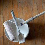 Målarfärg, pensel och roller. Arkivbild.