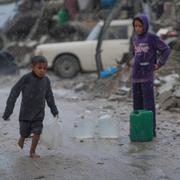 En pojke springer barfota i regnet i Gaza stad. 