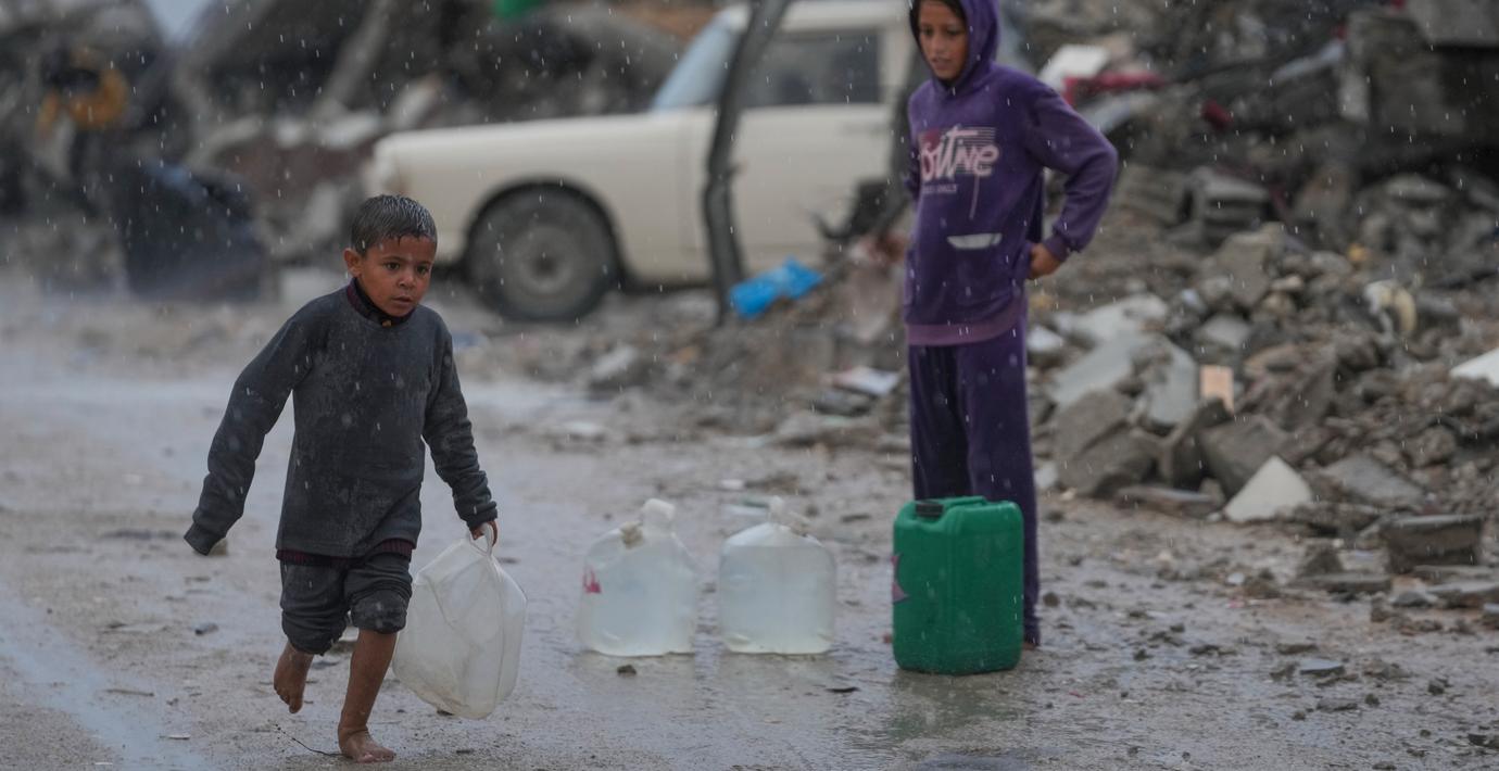 En pojke springer barfota i regnet i Gaza stad. 