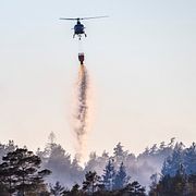 Arkivbild på helikopter som vattenbombar under en skogsbrand.