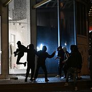 Ungdomar krossar fönster till en butik i samband med våldsamma protester i Paris.