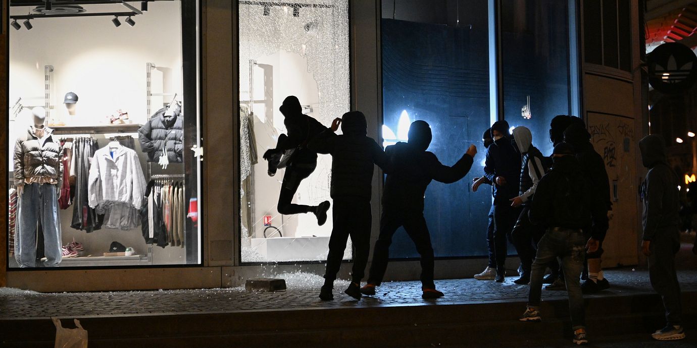 Ungdomar krossar fönster till en butik i samband med våldsamma protester i Paris.