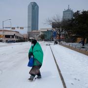 Arkivbild: En kvinna invirad i en filt går över gatan i centrala Dallas i vinterkylan förra veckan. 