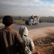 Två pojkar ser en lastbil lastad med möbler och andra tillhörigheter söder om Idlib på julaftonen.