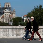 Två personer med munskydd passerar förbi Notre-Dame-katedralen i Paris under måndagen den  27 april.