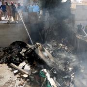 Människor försöker släcka elden från det kraschade planet i Karachi. 