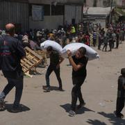 Palestinier som bär mjölpåsar genom Gaza. Akribild från 12 juli.