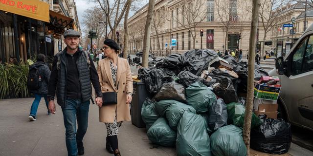 Un couple, main dans la main, passe devant l'un des tas d'ordures éparpillés dans une grande partie de Paris, le 13 mars 2023. Lewis Joly/AP