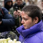 En ung kvinna som skadades i branden lägger ner blommor vid ett minnesmärke för offren i Crans-Montana tidigare i februari.