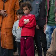 Barn står vid döda kroppar vid  Al Aqsa-sjukhuset på fredagen.