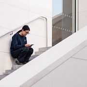 En kvinna kollar på sin telefon utanför en galleria i Peking.