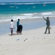 En polis gestikulerar till människor på stranden efter attacken.