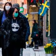 Turister bär ansiktsskydd under en promenad i Gamla stan i Stockholm. 