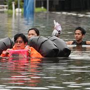 Människor som vadar genom det höga vattnet i Bangkok.