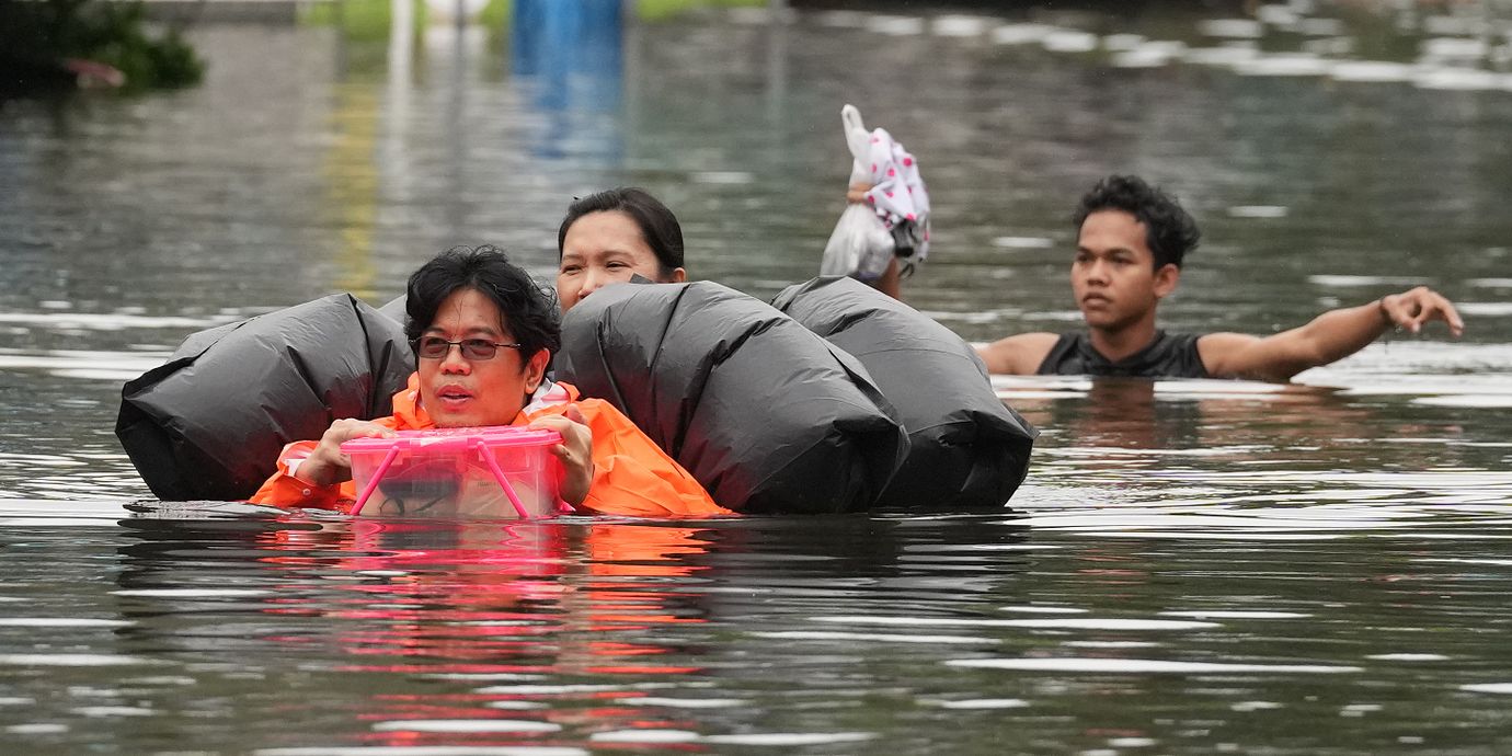 Människor som vadar genom det höga vattnet i Bangkok.