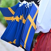 Illustrationsbild: Fanbärare i folkdräkt med svenska flaggan.