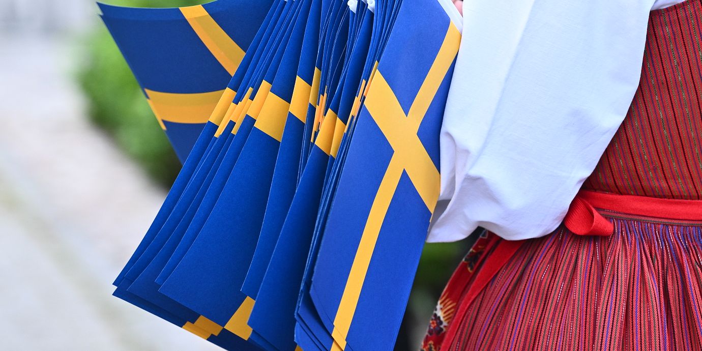 Illustrationsbild: Fanbärare i folkdräkt med svenska flaggan.