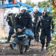 Poliser kör bort en demonstrant i skottkärra i Lützerath, Tyskland.