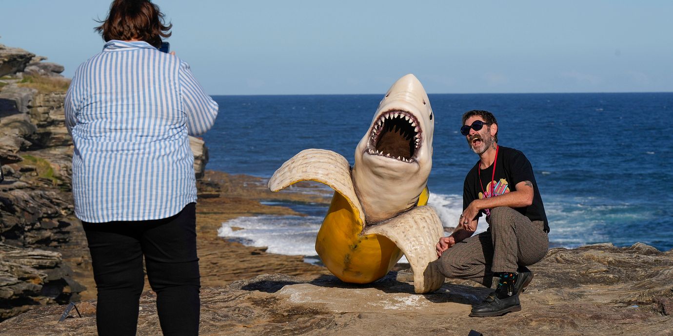 Illustrationsbild, Australien. En man poserar vid skulpturer på en konstutställning vid Bondi Beach i Sydney.