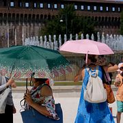 Överhettade turister skyddar sig från solen med paraplyer i Milano förra året.