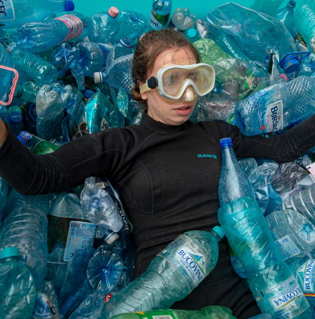 An activist gestures in an inflatable pool filled with PET plastic bottles during a protest outside the environment ministry demanding the introduction of the deposit refund scheme that will stimulate the population to recycle in Bucharest, Romania, Thursday, June 3, 2021.  Alexandru Dobre / AP