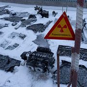 Delar av en drönare efter en rysk attack och en skylt som varnar för radioaktivitet i Tjernobyl, Ukraina, den 14 februari 2025. 