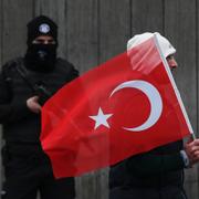 En man med turkisk flagga går förbi en polis under en minnesstund för offren på nattklubben i Istanbul.