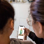 Tonåring kollar sociala medier på sin mobil tillsammans med vuxen.