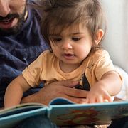 Föräldraledig pappa läser en saga för sin dotter.