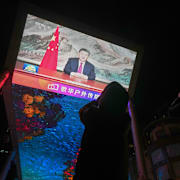 En kvinna tittar på Xis tal på en storbildsskärm.