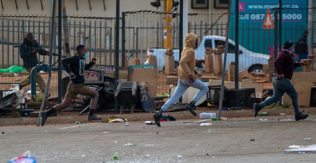 En civilklädd polis skjuter gummikulor mot plundrare på tisdagen. Themba Hadebe / TT NYHETSBYRÅN