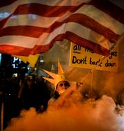 En demonstrant viftar med en amerikansk flagga under nattens protester mot premiärminister Benjamin Netanyahu i Tel Aviv i natt. Demonstranterna kräver att Netanyahu sluter ett avtal med Hamas. 