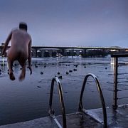 En man hoppar i vattnet  efter att ha bastat i Tantolunden i Stockholm. Bilden är tagen 2018.