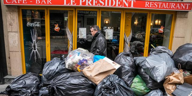 Un homme tente de trouver son chemin sur le petit morceau de trottoir qui se dresse encore entre lui et les ordures entassées devant le Café Le Président à Paris le 21 mars 2023. Michel Euler/AP