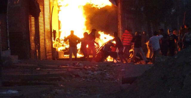 En grupp demonstranter sätter eld på en affär. TT NYHETSBYRÅN