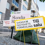 Skyltar från olika mäklarfirmor gör reklam för lediga lägenheter. Illustrationsbild.
