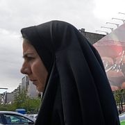 En kvinna går framför en storbildsskärm som visar Irans nye högste ledare Mojtaba Khamenei.