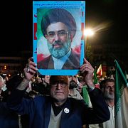 En demonstrant håller i en bild på Irans högsta ledare ayatollah Mojtaba Khamenei.