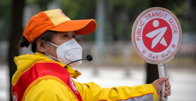 Trafikvakt bär munskydd i Peking. Mark Schiefelbein / AP