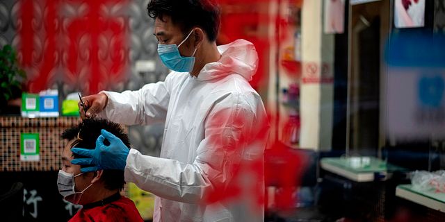 Frisör med skyddsdräkt och ansiktsmask återupptar nu verksamheten NOEL CELIS / TT NYHETSBYRÅN