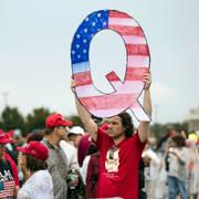 En man håller upp ett skylt med ett Q för Qanon under ett Trump-rally 2018. 